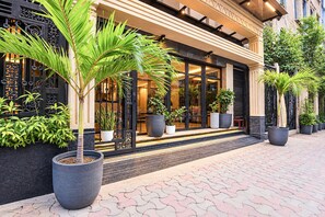 A building with a modern facade, large windows, and a variety of potted plants. - Deluxe Room Alamin International (Kolkata)