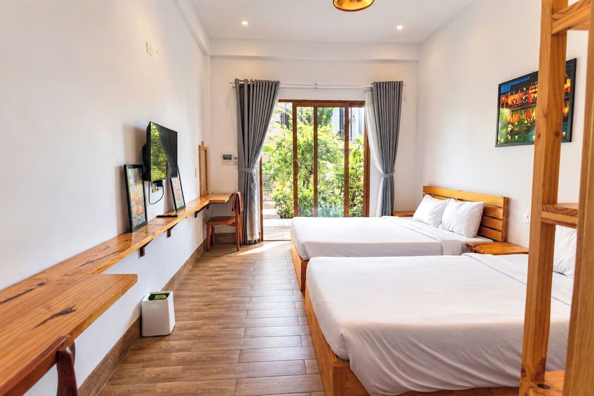 Ein Hotelzimmer mit zwei Betten, einem Schreibtisch, einem Stuhl, einem Fernseher und einem Fenster mit Vorhängen.