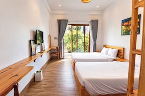 Ein Hotelzimmer mit zwei Betten, einem Schreibtisch, einem Stuhl, einem Fernseher und einem Fenster mit Vorhängen.
