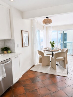 A modern kitchen with white cabinets, a dishwasher, and a dining area with a table and chairs. - Steps to the Beach, Quiet, New, Intuit, Crypto, Sofi, LAX, Venice, Santa Monica (Manhattan Beach)