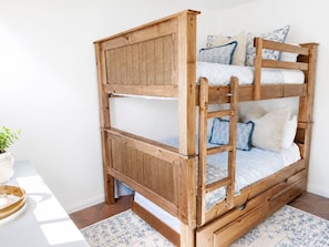 Een stapelbed met houten frame, twee kussens en een klein lade.
