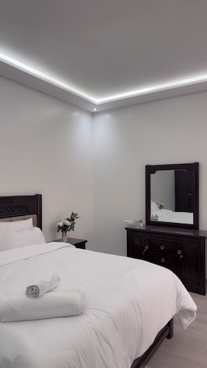 A modern bedroom with a large bed, a dark wooden dresser, and a mirror. - Dar Lalla Yasmina Guesthouse 5-bedroom bed with private bathroom in  Tangier (Tanger)
