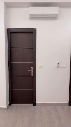 A room with a dark wooden door, a white wall-mounted air conditioner, a wall switch, and a thermostat. - Dar Lalla Yasmina Guesthouse 5-bedroom bed with private bathroom in  Tangier (Tanger)
