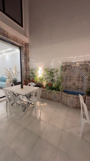 A dining area with a table and chairs, a patterned wall, and a window with a view. - Dar Lalla Yasmina Guesthouse 5-bedroom bed with private bathroom in  Tangier (Tanger)
