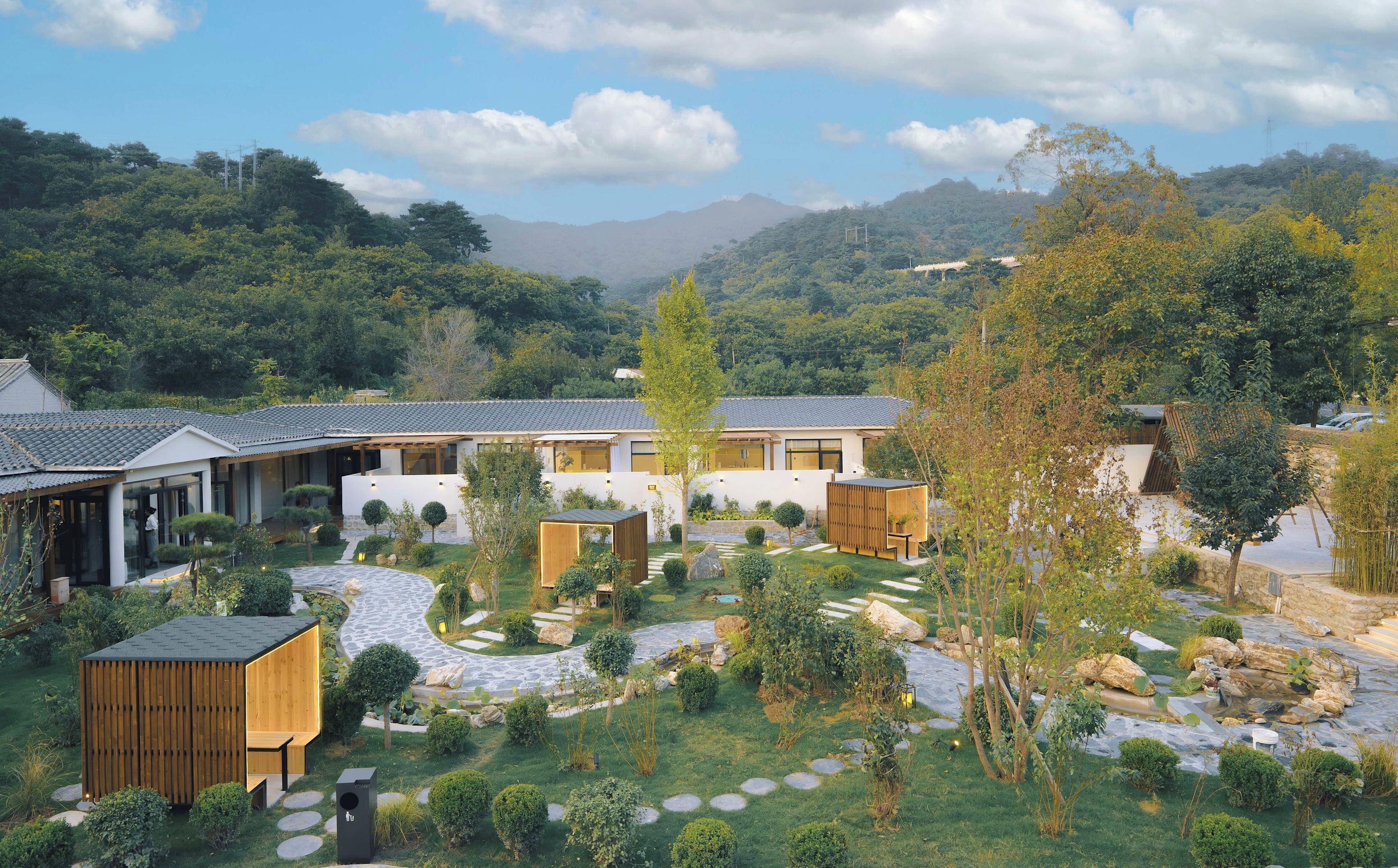 Un edificio moderno con un patio interior, rodeado de exuberante vegetación y montañas al fondo.