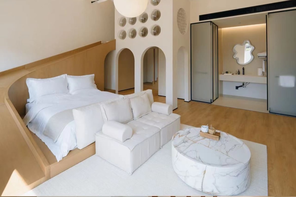 Moderni hotellihuone, jossa on sänky, oleskelualue ja kylpyhuone, jossa on pesuallas.