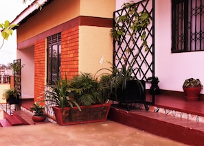 Un bâtiment à la façade en briques rouges, doté d’un portail en métal noir et agrémenté de plantes en pot.
