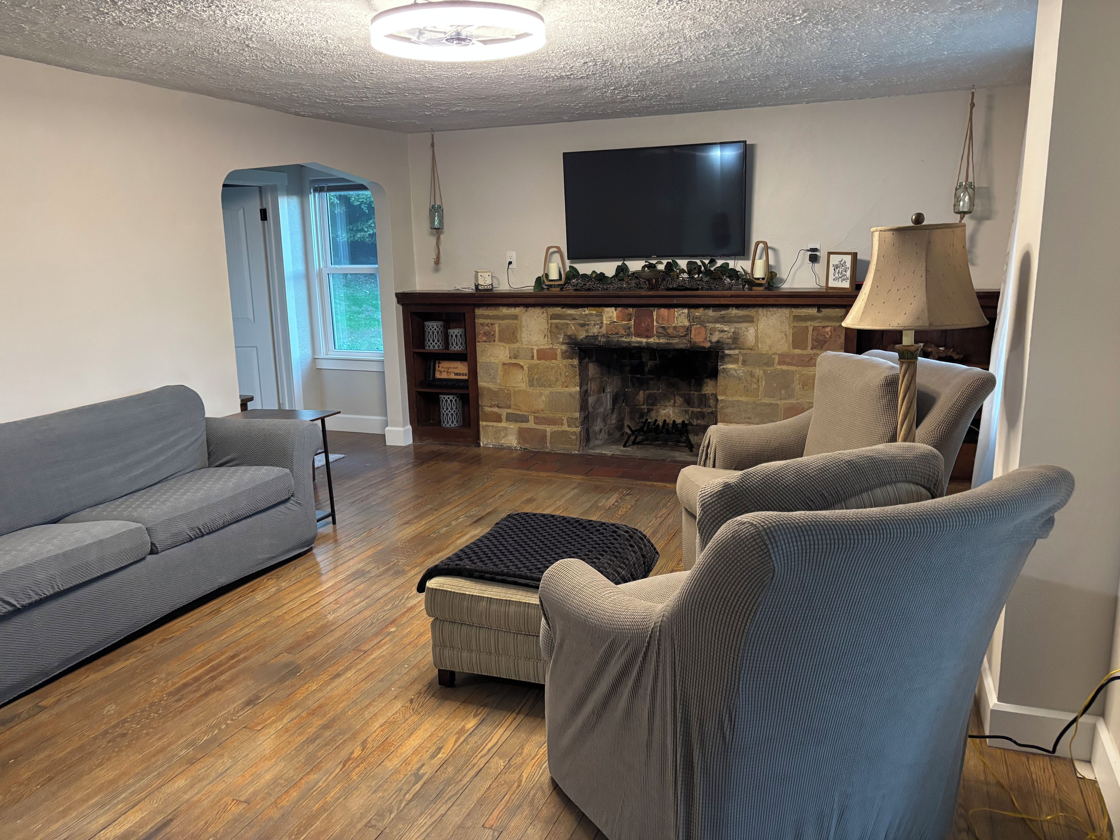 Ein Wohnzimmer mit Kamin, Flachbildfernseher, Sofa und Sessel.