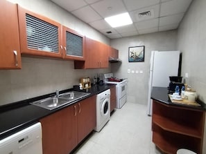 A compact kitchen with a washing machine, a stove, and a refrigerator. - Zigzag Tower B-Honeymoon Suit, 2 Bedroom at 32 floor In Pearl-3201B (Lusail)