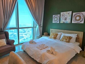 A hotel room with a large bed, a sofa, and a view of the city through the window. - Zigzag Tower B-Honeymoon Suit, 2 Bedroom at 32 floor In Pearl-3201B (Lusail)