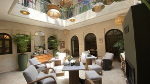 Eine großzügige Lobby mit hoher Decke, mehreren Sitzbereichen und einem zentralen Tisch mit Dekoration.