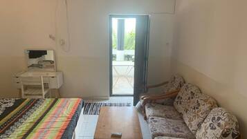 A room with a bed, a sofa, a small table, a desk, and a window.