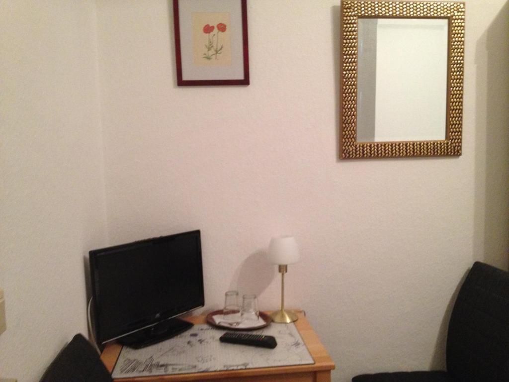 Una habitación con una televisión sobre una mesa de madera, una lámpara y un cuadro en la pared.