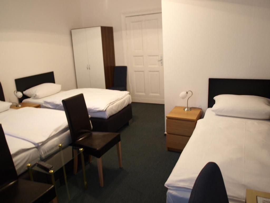 Ein Hotelzimmer mit zwei Betten, einem Schreibtisch, einem Stuhl, einem Kleiderschrank und einer Tür.