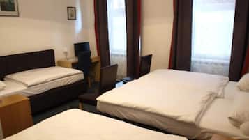 Ein Hotelzimmer mit zwei Betten, einem Schreibtisch, einem Stuhl und einem fenster mit Vorhängen.