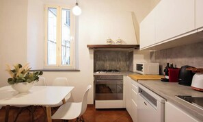 Cuina compacta amb taula de dinar, cadires, fogó, microones i cafetera.