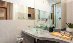 Casa de banho moderna com duas lavatórios de vidro, um espelho grande e um tabuleiro de madeira com artigos de higiene pessoal.