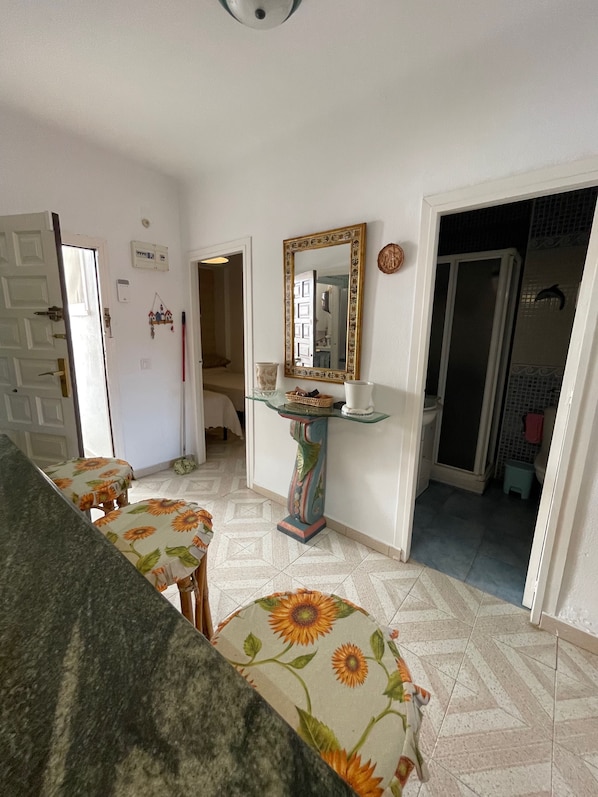 Una habitación con un sofá, una mesa con un espejo decorativo y una puerta que da a otra estancia.