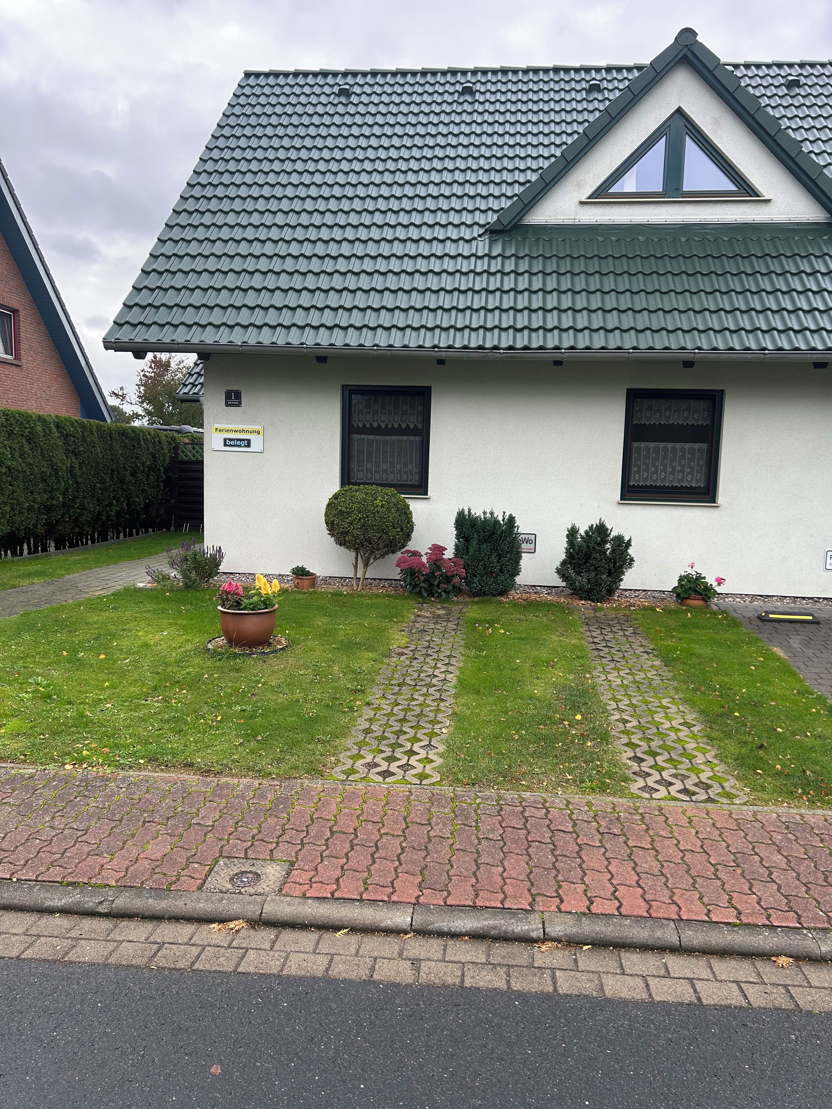 Una casa a un piano con tetto in tegole, un piccolo giardino antistante con vialetto lastricato e un cartello che indica che si tratta di un'abitazione familiare.