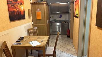 A compact kitchen with modern appliances, a dining area with a wooden table and chairs, and artwork on the walls.