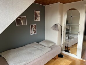 Ein Schlafzimmer mit einem Bett, einer Stehlampe und einer Wand mit gerahmten Bildern.