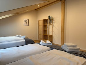 Een hotelkamer met twee bedden, een houten garderobe en een ingelijste foto aan de muur.