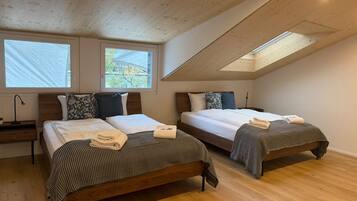 Een slaapkamer met twee bedden, houten vloeren en dakramen.