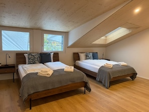 Een slaapkamer met twee bedden, houten vloeren en dakramen.