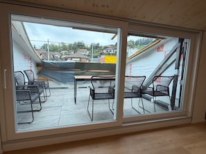 Una stanza con un'ampia porta-finestra scorrevole che dà su un patio esterno con vista su un quartiere residenziale.