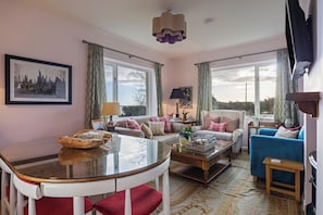 A well-lit living room with a sofa, armchairs, a coffee table, and a dining table. - Delightful Cottage, Strangford Lough, County Down (Newtownards)