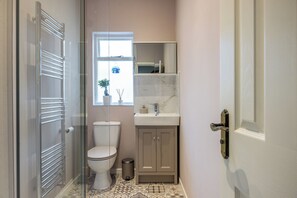 Un baño con inodoro, lavamanos, armario y cabina de ducha de vidrio.