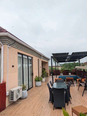 Eine Terrasse im Freien mit Pool, Sitzbereich und überdachtem Bereich.