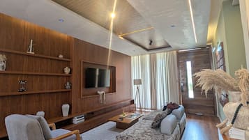 Ein modernes Wohnzimmer mit Holzboden, einer Sofagarnitur, einem Couchtisch und einem an der Wand befestigten Flachbildfernseher.