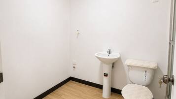 A small, clean bathroom with a toilet, sink, and a wooden floor.