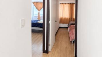 A hotel room with a bed, a window with curtains, and a view of the city.