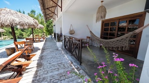 Une terrasse en bois avec des meubles d’extérieur, un hamac et une piscine.