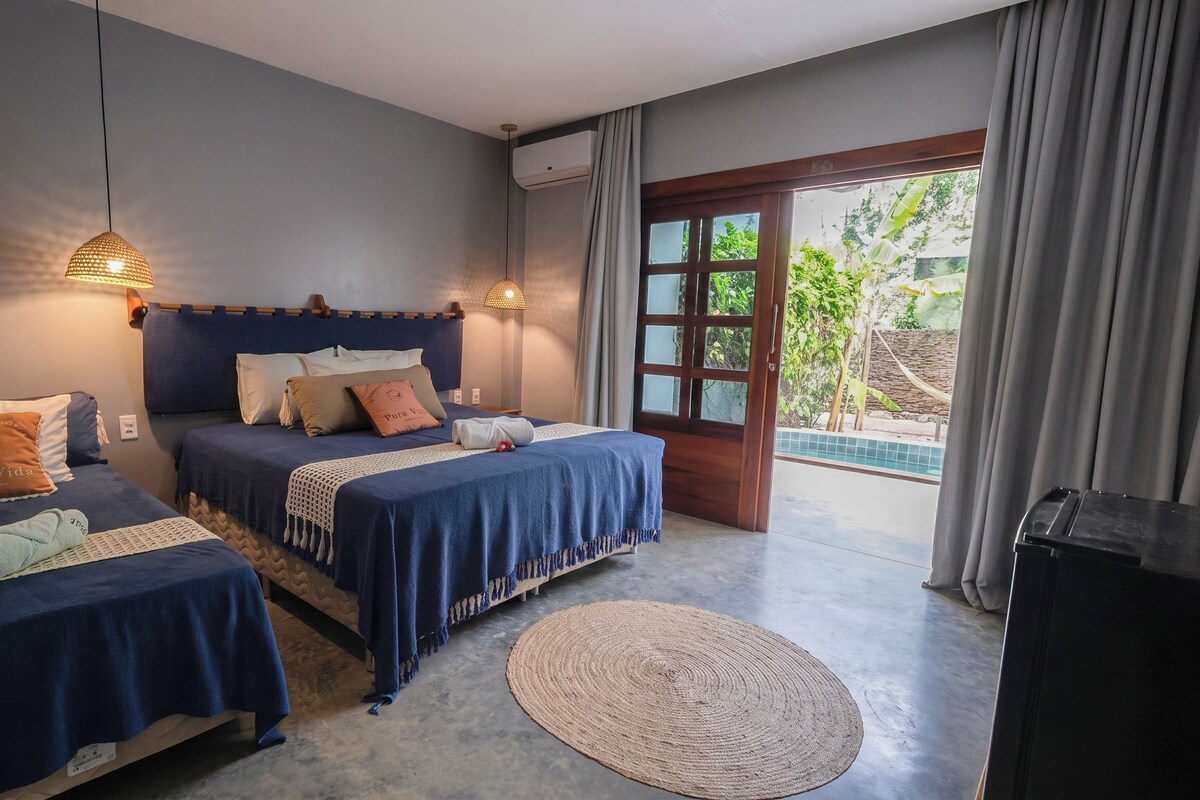 Une chambre d’hôtel avec deux lits, une grande fenêtre et une vue sur la verdure environnante.