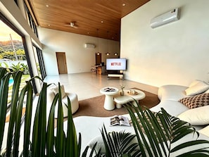 Una sala de estar moderna con una televisión de pantalla plana, una mesa de centro y un sofá.