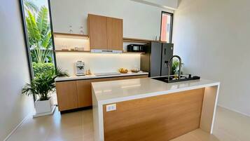 A modern kitchen with a central island, wooden cabinets, a built-in microwave, and a sink.