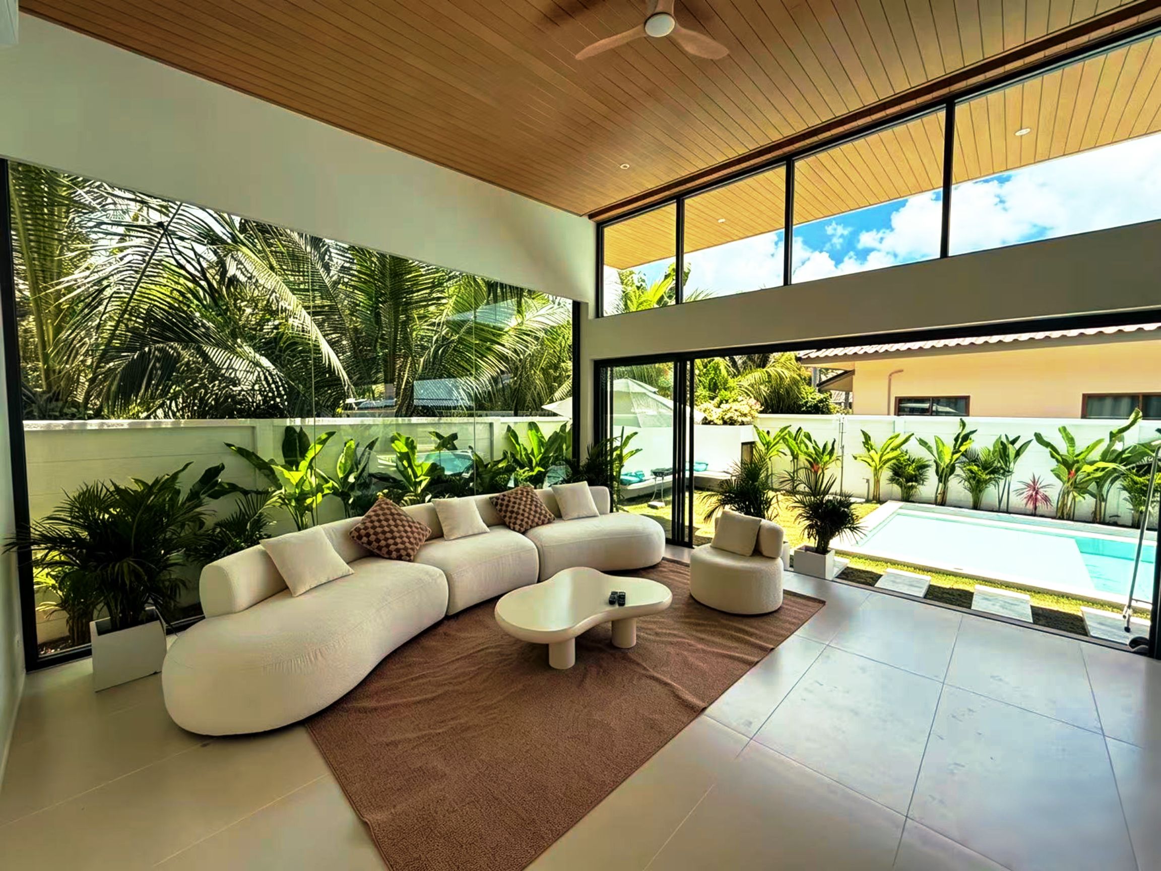 A modern living room with a sectional sofa, a coffee table, and a view of a swimming pool.