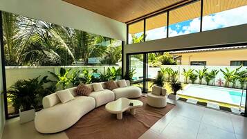 A modern living room with a sectional sofa, a coffee table, and a view of a swimming pool.