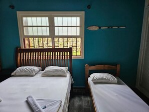 A room with two beds, a window, and a wall-mounted decorative item. - Pousada Nevada Enseada (Ubatuba)