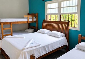 A room with a bunk bed, a single bed, and a window with a view of greenery. - Pousada Nevada Enseada (Ubatuba)