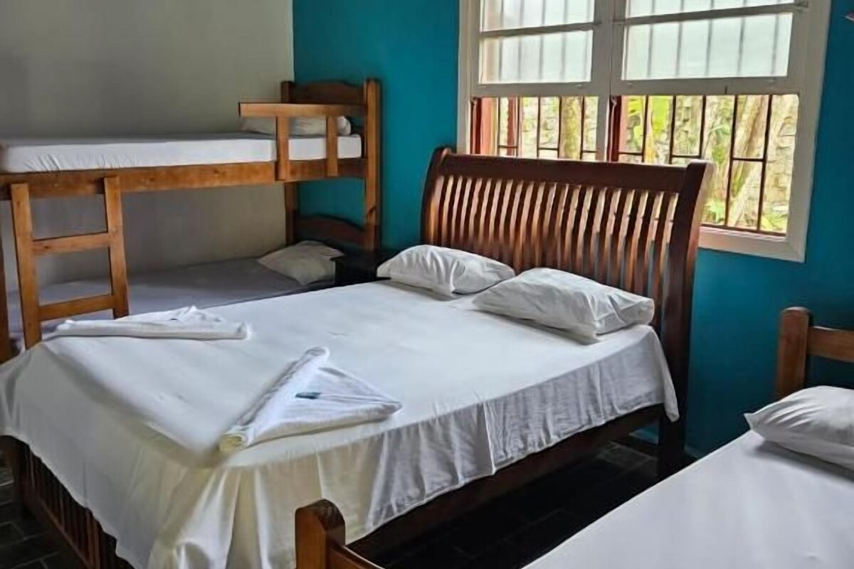 A room with bunk beds, a window with blinds, and a ceiling fan.