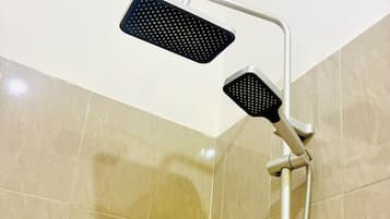 Une douche équipée d’un pommeau de douche à main et d’une robinetterie murale.