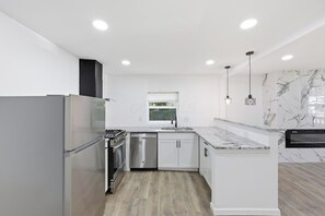 Una cocina moderna con armarios blancos, electrodomésticos de acero inoxidable y un salpicadero de mármol.
