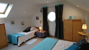 A bedroom with a bed, a bedside table with a lamp, a wardrobe, a window with curtains, and a skylight. - New Listing (Autrechêne)