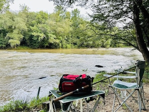 Un río con una silla de camping y una mochila roja a la orilla del agua.