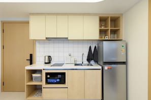 A compact kitchen with a built-in dishwasher, a stainless steel refrigerator, and a coffee maker. - Sunset Rooftop Pool | 2BR near Kamala Beach | Gym 211 (Tambon Kamala)