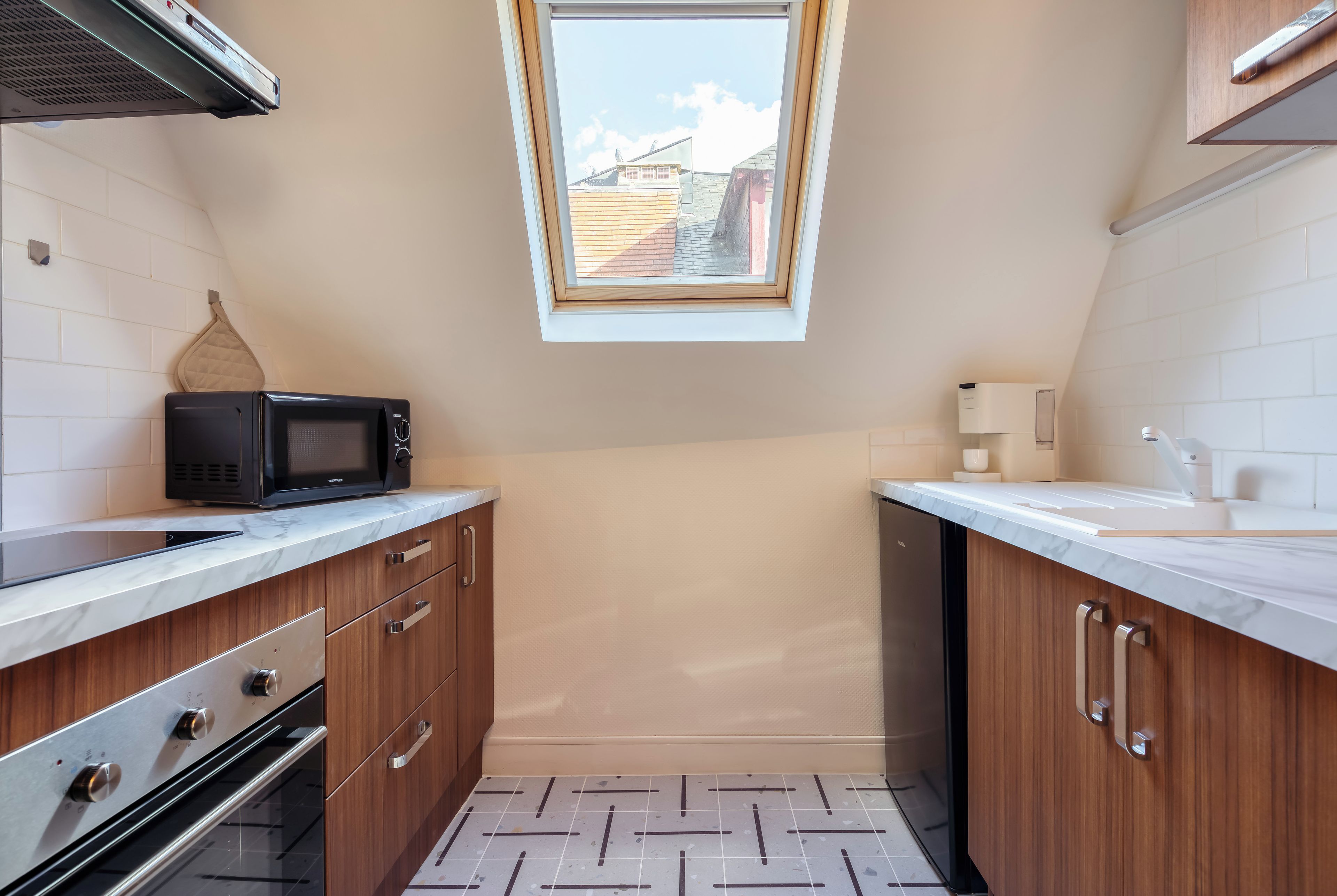 A compact kitchen with a microwave, oven, and sink.